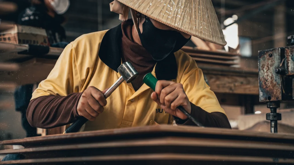 Female artisan operating woodworking machinery on the interior wooden door production line at Chan Tam factory.