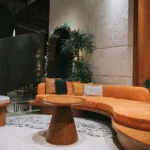 A luxurious hotel reception lobby featuring premium wall decoration crafted from theShaper's crown cut American Black Walnut wood veneer, showcasing rich espresso undertones and majestic, sweeping natural cathedral grain arches.