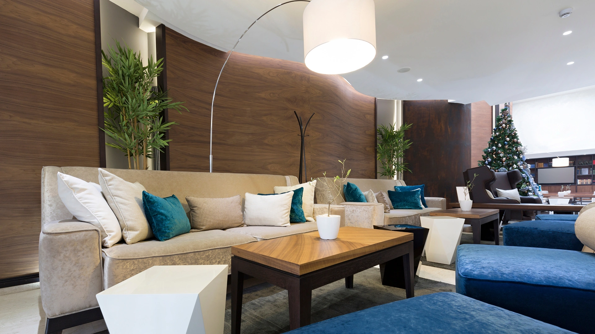 An upscale hotel social lounge featuring custom wall paneling designed with theShaper's crown cut American Black Walnut wood veneer, displaying exquisite deep chocolate tones and striking cathedral patterns that elevate the shared space.