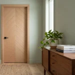 A square photograph of a natural white oak wooden interior door with a book-matched chevron pattern.
