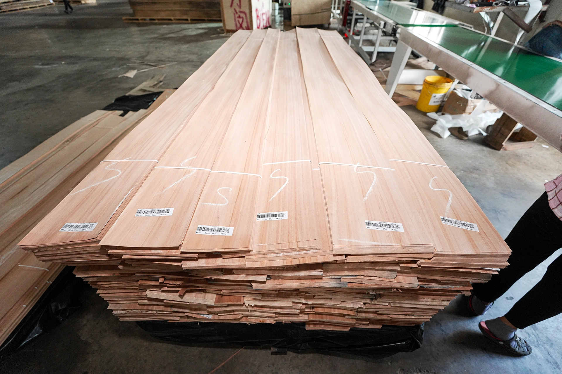 Bundled pallets of premium Red Grandis quarter cut wood veneer sheets, securely wrapped and prepared for international shipping at theShaper facility.