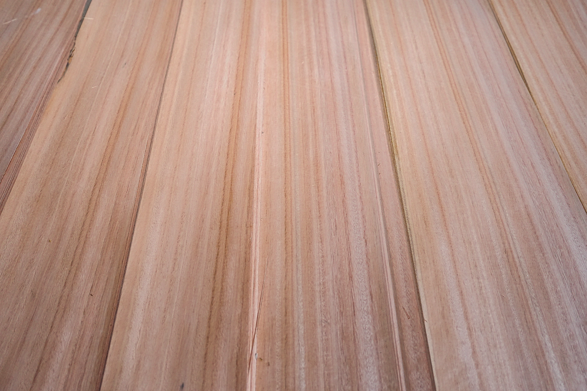 High-angle close-up shot showcasing the straight, parallel grain lines and smooth texture of Red Grandis quarter cut veneer sheets.