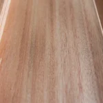 Close-up of Red Grandis wood veneer showing its natural, elegant warm rosy-pink and light reddish-brown coloration under studio lighting.