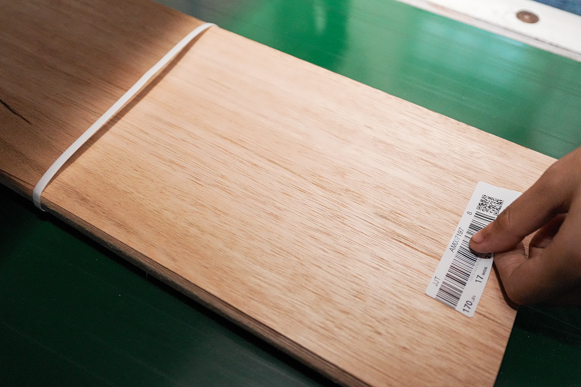 Close-up of a product specification label and FSC certification tag attached to a bundle of Red Grandis quarter cut wood veneer by theShaper.