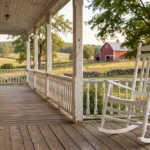 A photorealistic 3D rendering of a white American country style rocking chair on a classic Boston-style colonial home porch with a wooden deck and elegant railings.