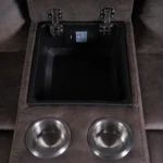 Center console storage compartment open with dual stainless steel cup holders on reclining loveseat.