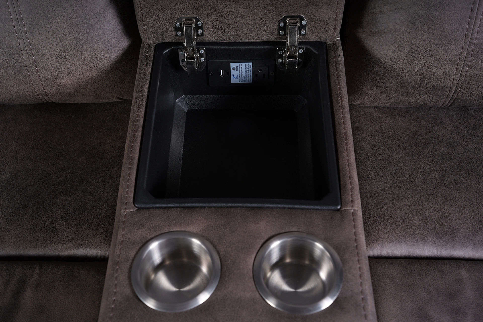Center console storage compartment open with dual stainless steel cup holders on reclining loveseat.