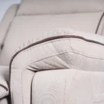 Close-up of wide padded armrest featuring tailored contrast piping trim on cream fabric.