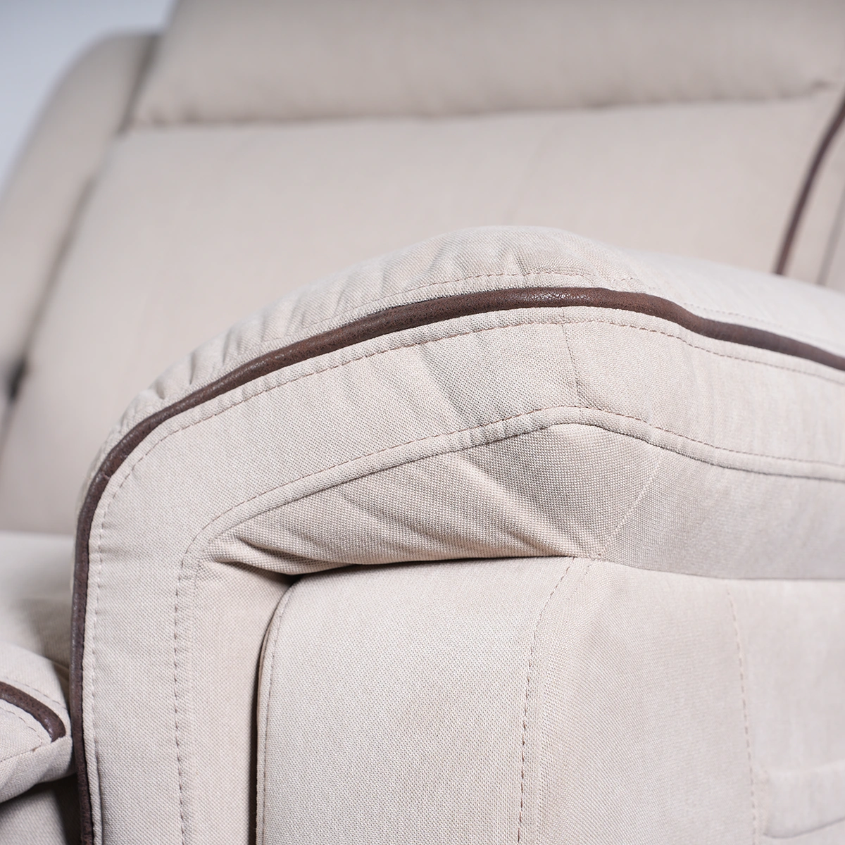 Close-up of wide padded armrest featuring tailored contrast piping trim on cream fabric.
