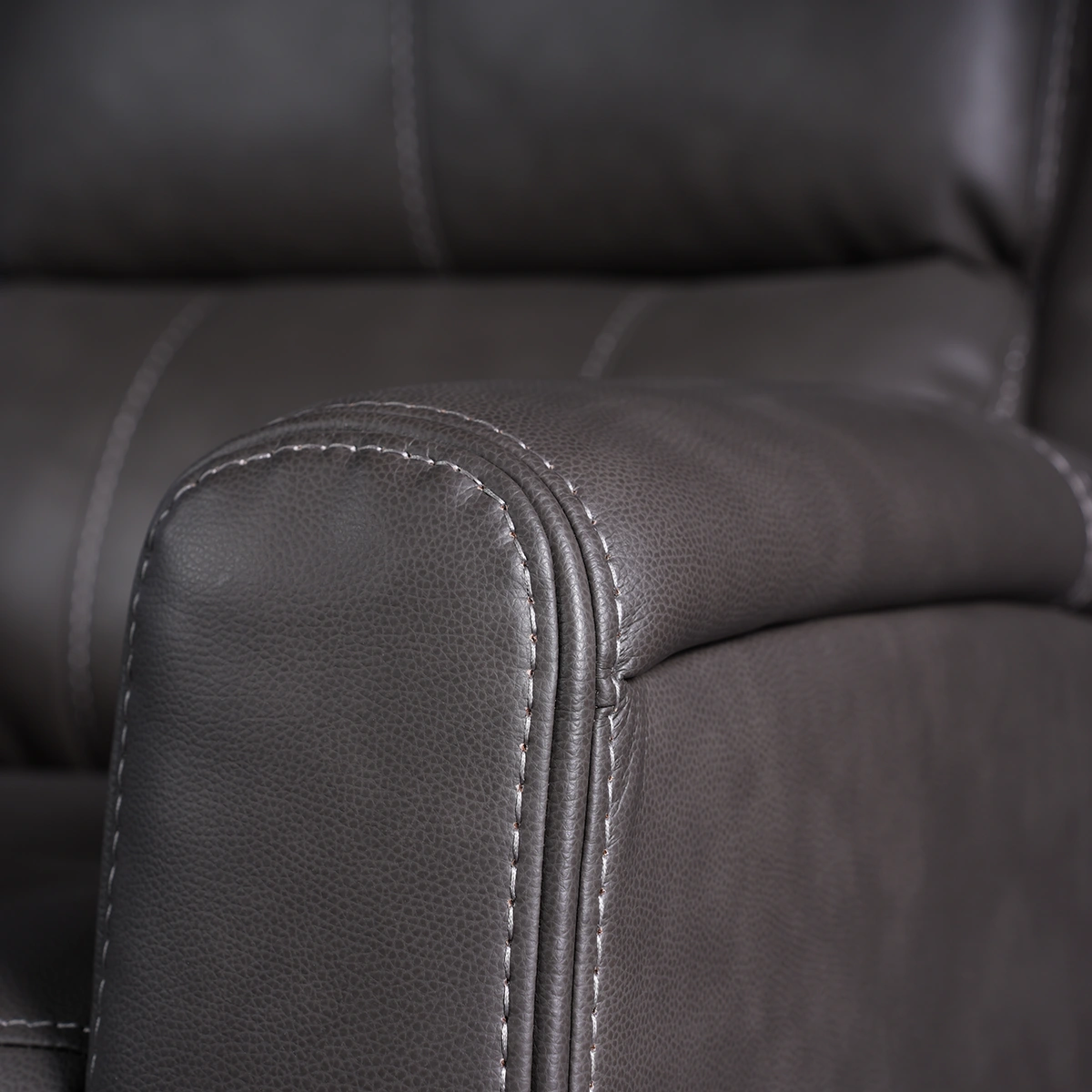 Close-up of curved track armrest showing precision contrast stitching and vegan leather texture.
