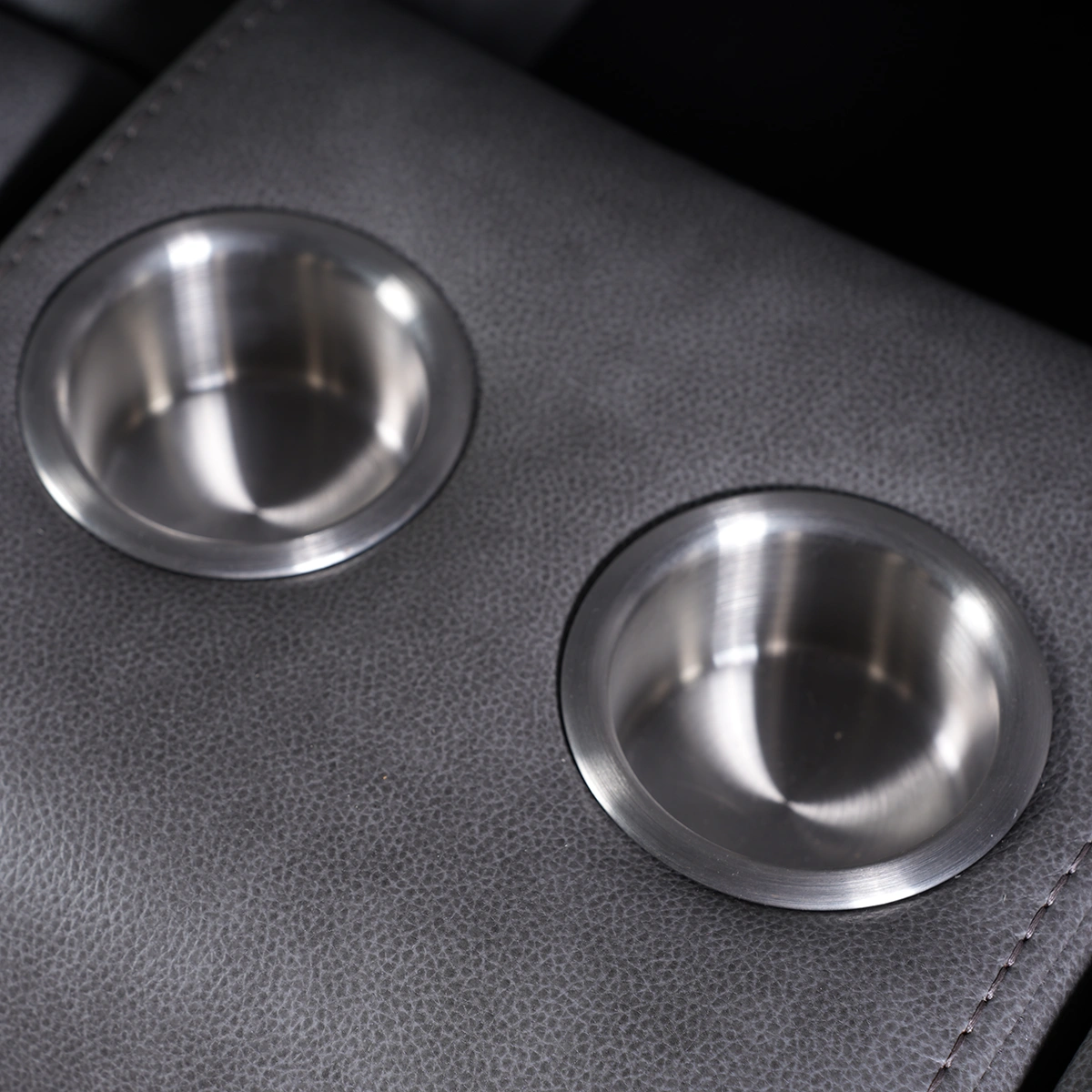 Close-up view of twin recessed stainless steel cup holders in center console.
