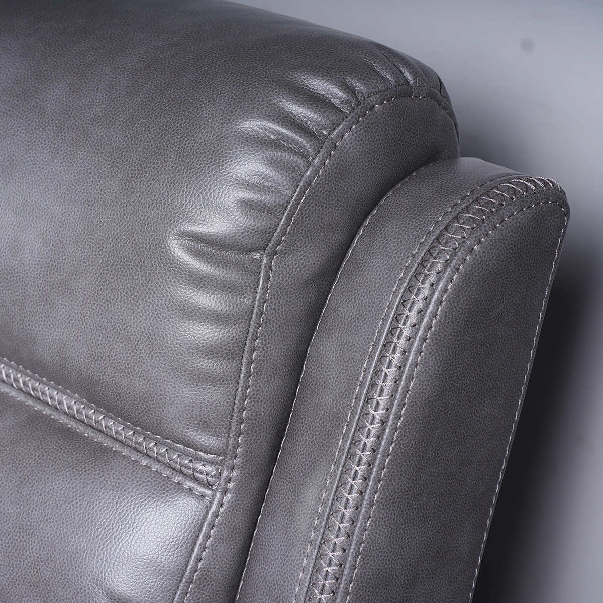 Close-up of tailored precision stitching and textured slate grey faux leather upholstery.