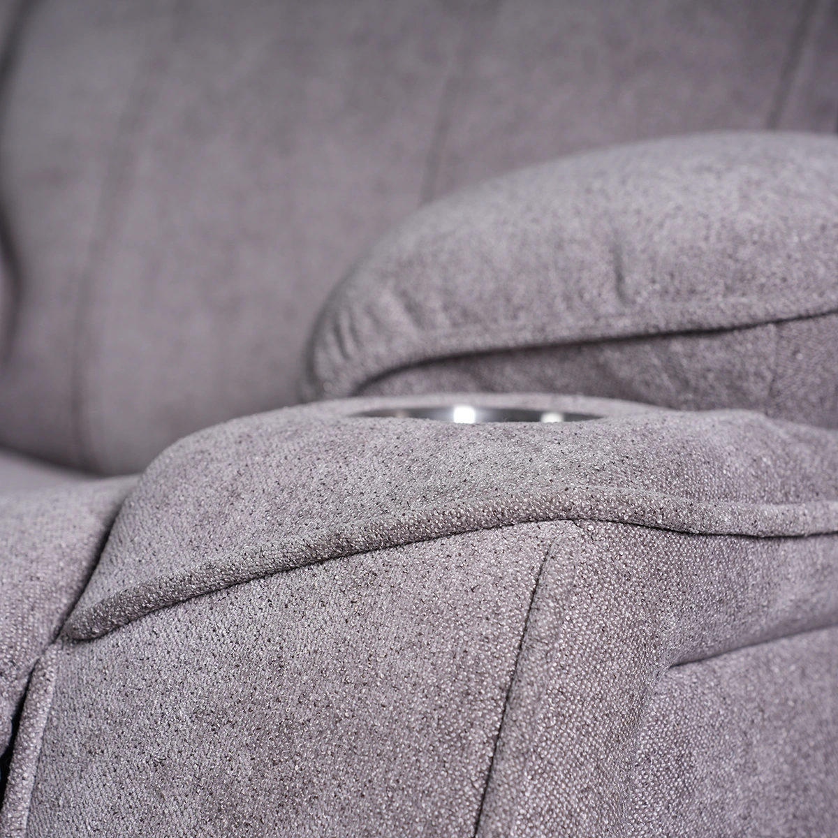 Close-up of overstuffed pillow-top armrest tailored in plush charcoal grey textured upholstery.