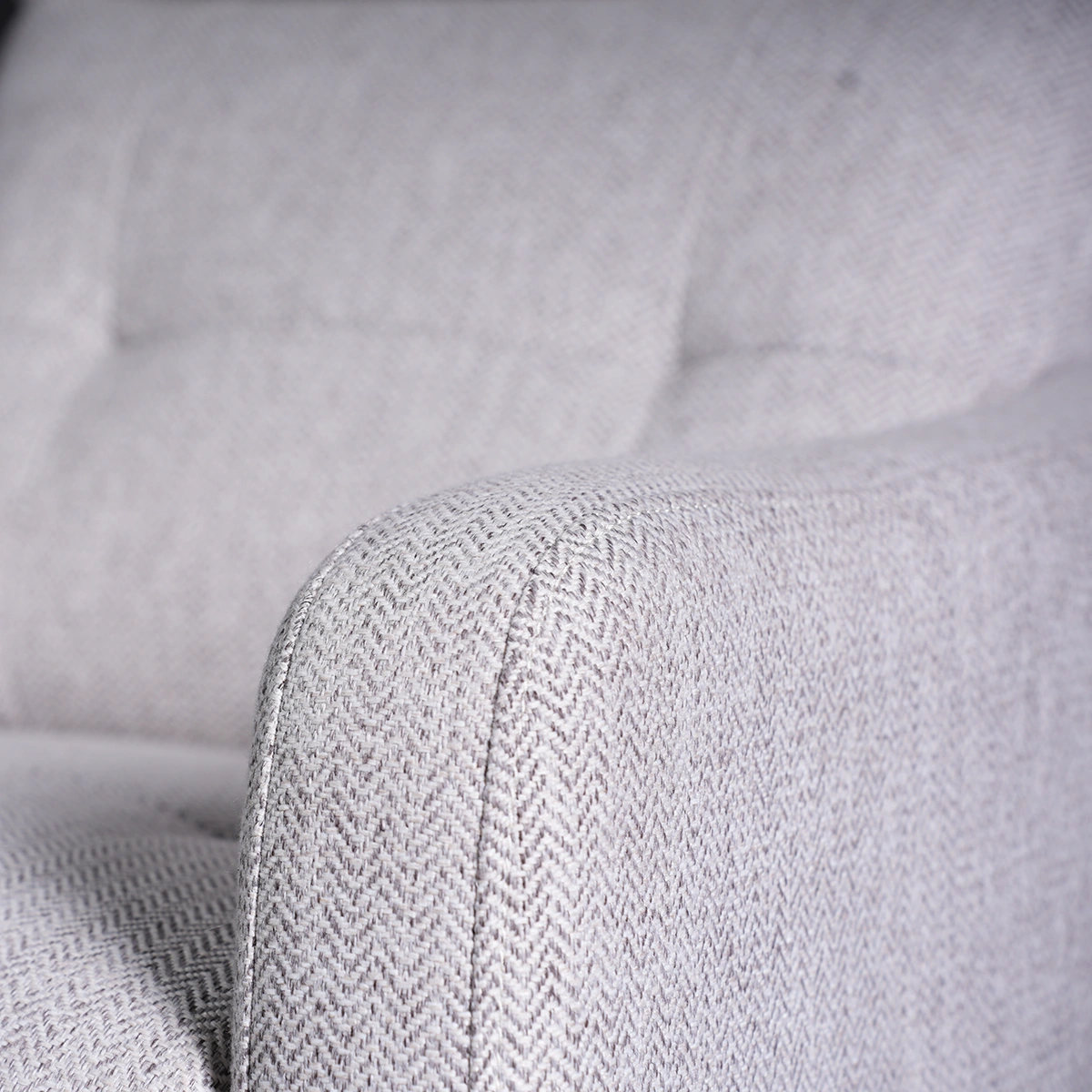 Close-up of slim padded track armrest showing crisp stitching and herringbone weave.