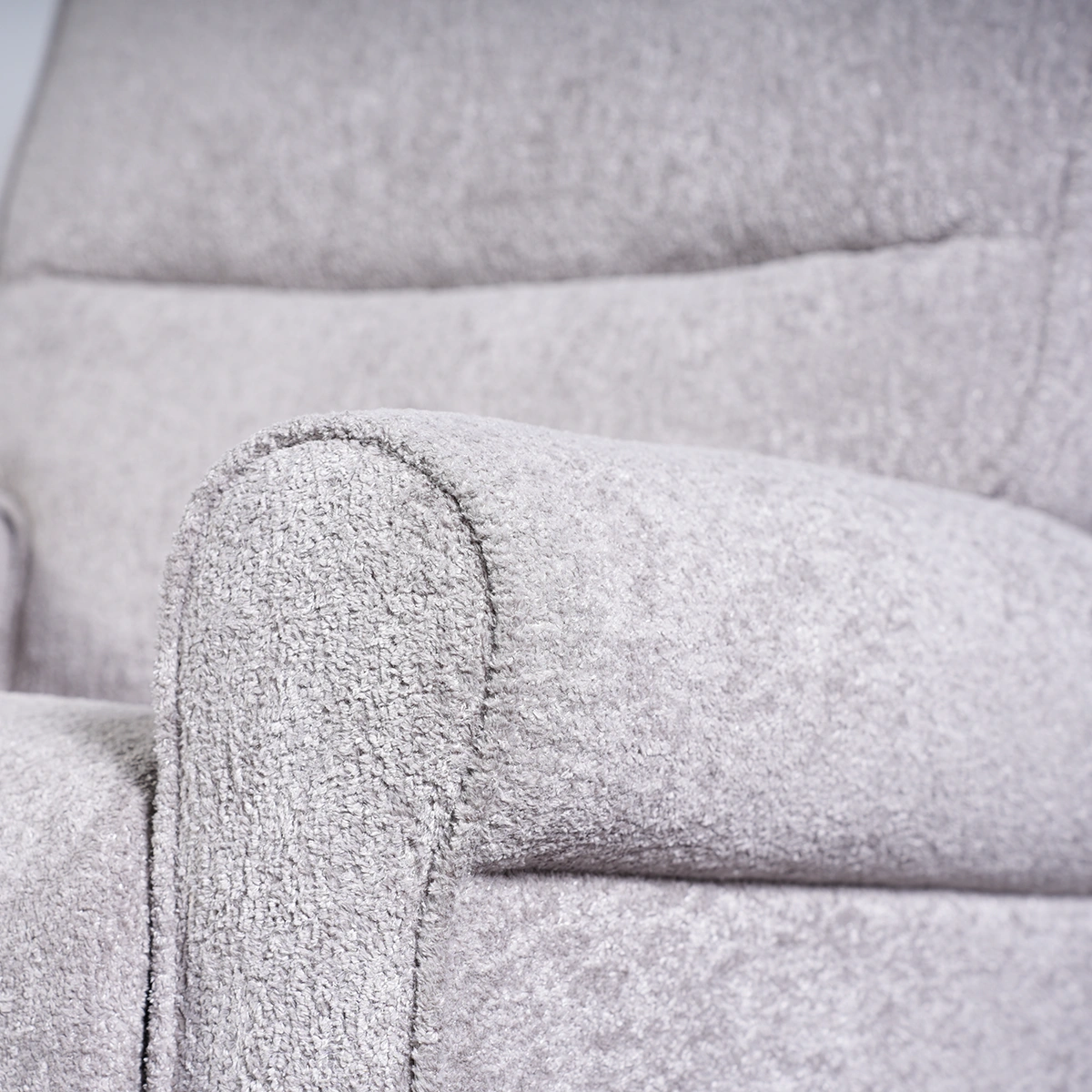 Close-up of classic rolled armrest showing tailored pleated detailing and light grey woven fabric.