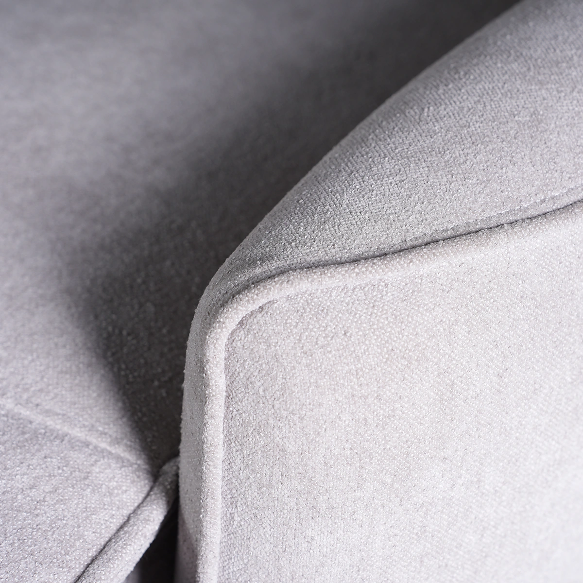 Close-up of tailored piped edge trim along the gently arched padded armrest.