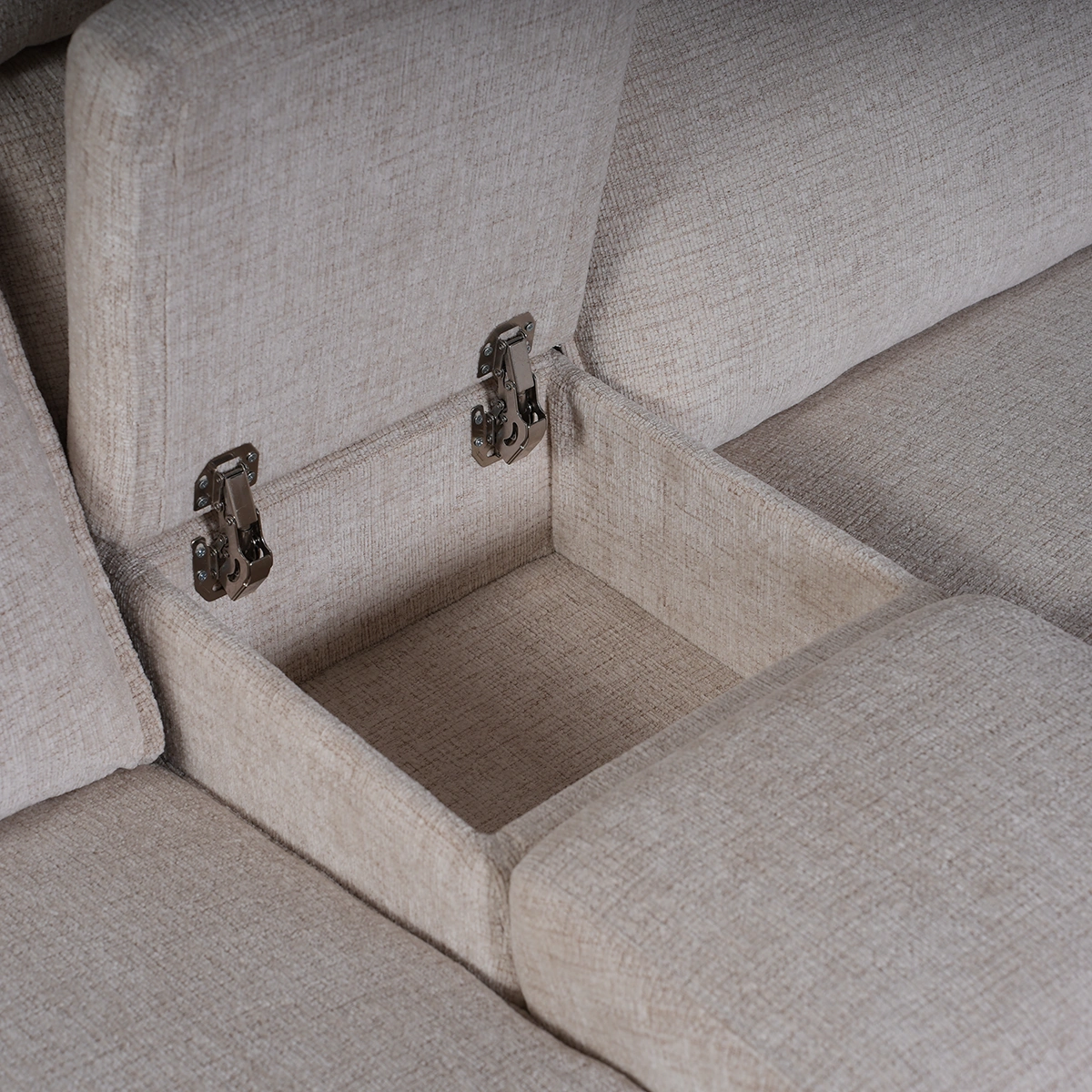 Close-up of open flip-top storage console with twin stainless steel cup holders on curved sectional.