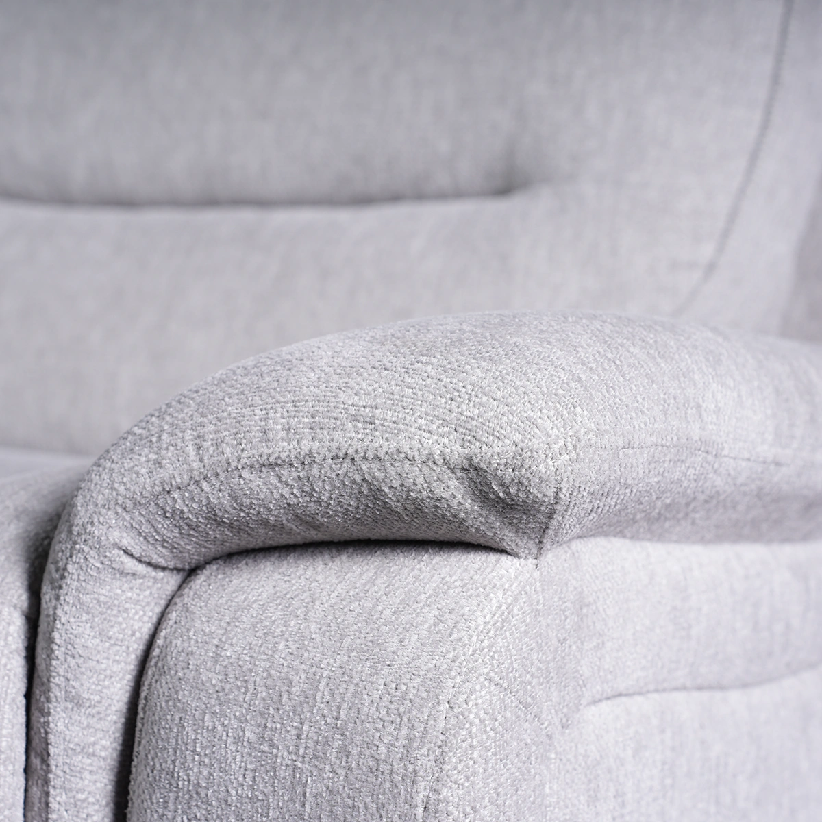 Close-up of deep-padded plush pillow-top armrest tailored in textured light grey fabric.